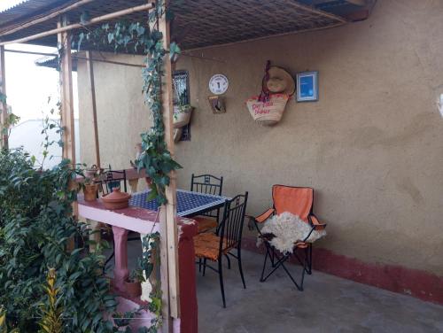 a patio with a table and chairs and a clock at Dar Lala Zhour in Aïn Bouchrik