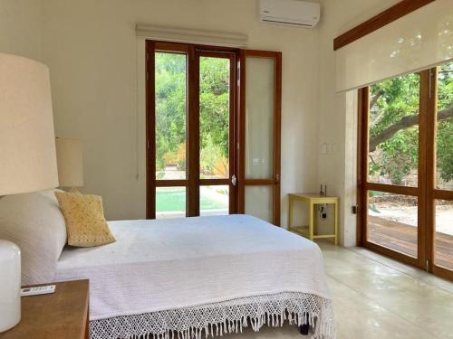 a bedroom with a large white bed and large windows at Hermosa Casa Antigua con Piscina Tropical in Mérida