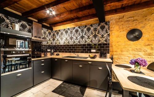 d'une cuisine avec des placards gris et un plafond en bois. dans l'établissement Le Secret d'Enoiseuses - Centre historique, à Sarlat-la-Canéda