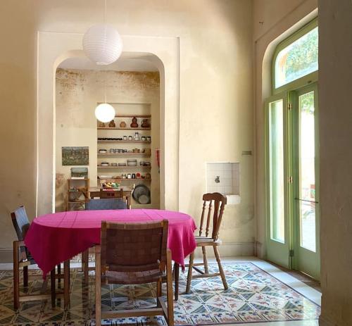 a dining room with a pink table and chairs at Hermosa Casa Antigua con Piscina Tropical in Mérida