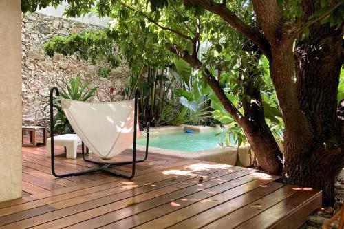 a chair sitting on a deck next to a swimming pool at Hermosa Casa Antigua con Piscina Tropical in Mérida