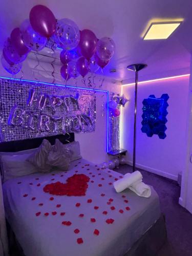 ein Schlafzimmer mit lila Ballons und ein Bett mit Herzen in der Unterkunft Luxury Urban Hideaway with private hot tub in Croydon