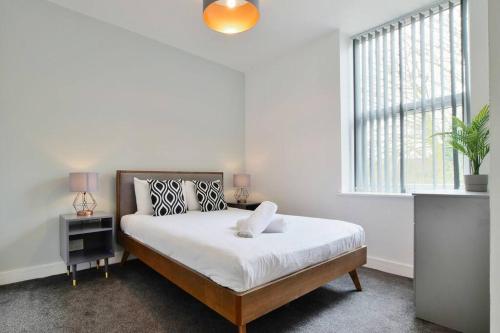 a white bedroom with a bed and a window at FREE PARKING - Charming 2-BR Flat near Salford Royal in Manchester
