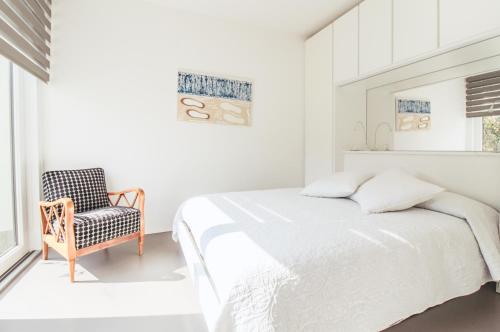 a white bedroom with a bed and a chair at La Sosta in San Siro