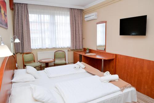 a hotel room with two beds and a flat screen tv at Major Panzió és Étterem in Hajdúszoboszló