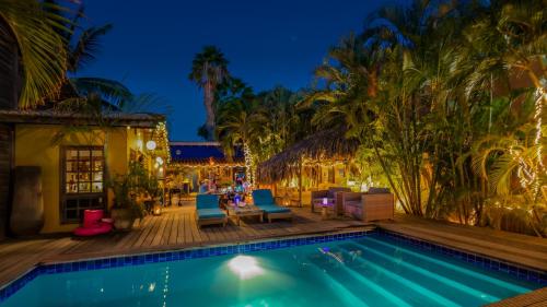 a swimming pool at night with blue chairs and palm trees at Casa Calexico in Kralendijk