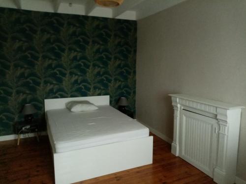a room with a white bed and a green wall at Maison Bretonne in Cléden-Cap-Sizun