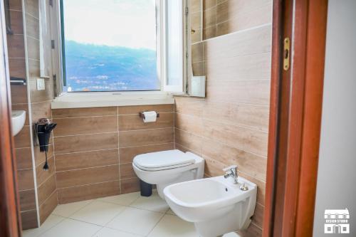 a bathroom with a toilet and a sink and a window at Villa Lena in Bellano