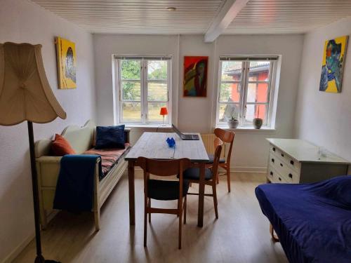 a room with a table and a bed and a table and chairs at Rummeligt byhus i Allinge med værelse i stueplan og havkig in Allinge