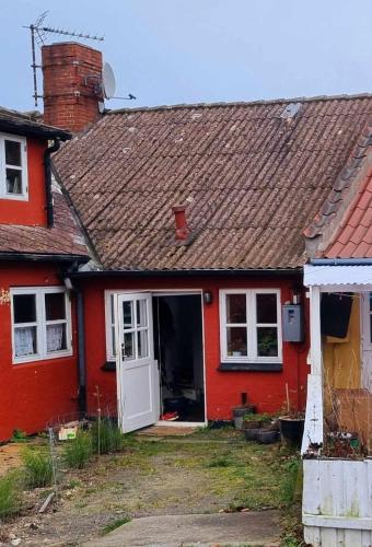 a red house with a white door at Helt byhus 120 kvm centralt med 2 soveværelser, 5 senge og havkig in Allinge
