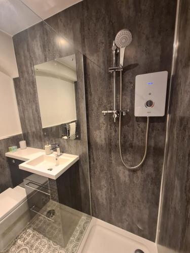 La salle de bains est pourvue d'une douche et d'un lavabo. dans l'établissement Meadowside Holiday Apartments, à Torquay