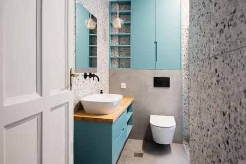 ein Badezimmer mit einem Waschbecken, einem WC und blauen Schränken in der Unterkunft Sofia Sunshine Serenity in Thessaloniki