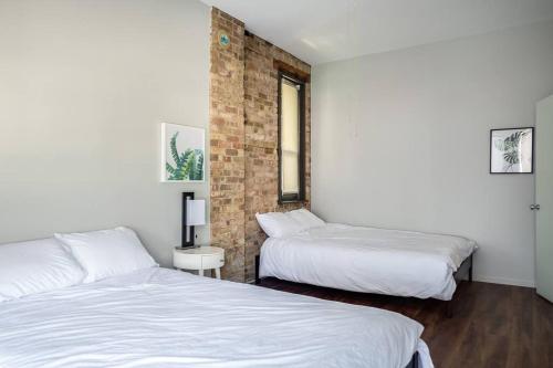 a bedroom with two beds and a brick wall at Luxury Downtown Penthouse with Private Rooftop in Chicago