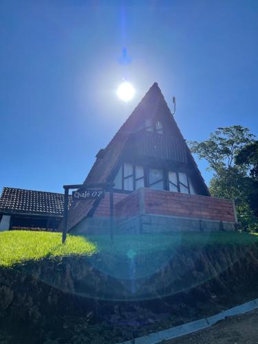 a house on a hill with the sun behind it at Pousada Scursel in Ibirama