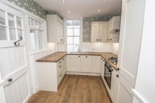 a kitchen with white cabinets and a wooden floor at City Chester Entire House Central in Chester