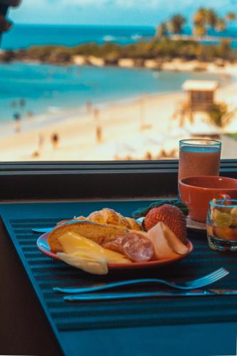 a plate of food on a table with a view of the beach at Marilyn Pousada Morro in Morro de São Paulo