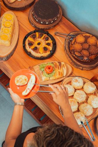 a person reaching for a plate of food on a table at Marilyn Pousada Morro in Morro de São Paulo