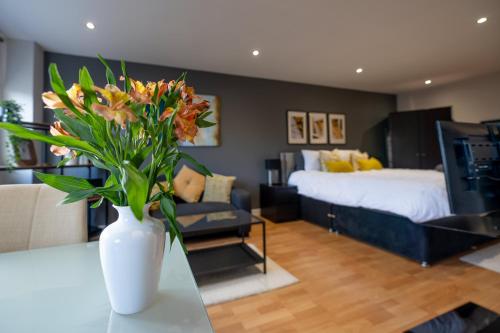 a vase with flowers on a table in a bedroom at Perfectly Located City Centre Studio Apartment - West One with FREE WIFI, GYM ACCESS, NETFLIX in Sheffield