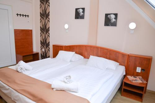 a bedroom with a bed with white sheets and towels at Major Panzió és Étterem in Hajdúszoboszló