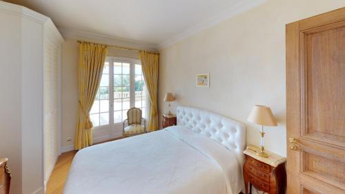 een slaapkamer met een wit bed en een raam bij Villa vue mer-piscine-jacuzzi-billard-homecinema in Mireval