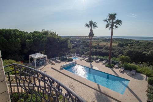 a balcony with a swimming pool and palm trees at Villa vue mer-piscine-jacuzzi-billard-homecinema in Mireval