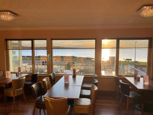 a restaurant with tables and chairs and large windows at Myrtle Bank Hotel in Gairloch