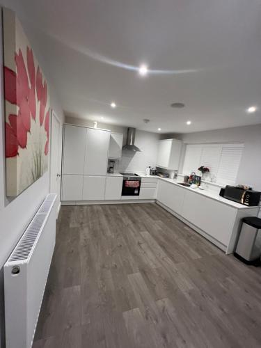 a kitchen with white cabinets and a wooden floor at Beautiful Shared One Bed Flat (Room/Front) in Strood