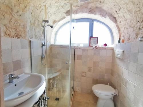 een badkamer met een douche, een toilet en een wastafel bij Trulli al Verde Viburno in Martina Franca