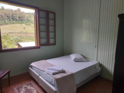 a small bedroom with a bed and a window at Colônia da Nona Angélica in Farroupilha