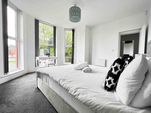 a white bedroom with a large bed with black and white pillows at FREE PARKING - Cosy 2-BR Flat near Salford Royal in Manchester