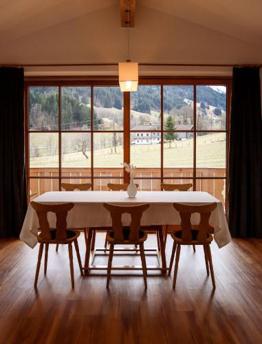 a dining room table with chairs and a large window at Apartment Vordermitterast in Kirchberg in Tirol