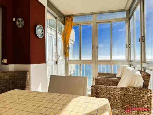 a dining room with a table and chairs and windows at Joya Mediterránea in Benicàssim
