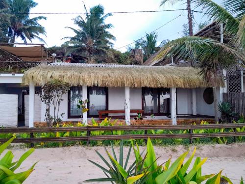 a house on the beach with a thatched roof at Casa do Índico in Praia do Tofo