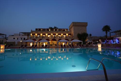 a large swimming pool at a hotel at night at Messapia Hotel in Marina di Leuca