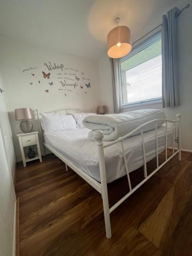 Cama blanca en habitación con ventana en The Green One, Sunbeach, Scratby - Two bed chalet, sleeps 5, free Wi-Fi, pet friendly, bed linen and towels included plus free entry to onsite clubhouse en Scratby