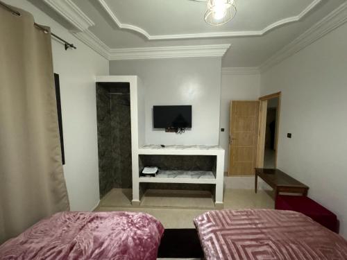a bedroom with a bed and a tv on the wall at Hotel Ahmed Ali in Dakhla