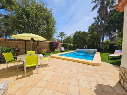 eine Terrasse mit Tisch und Stühlen und einem Pool in der Unterkunft Villa Comas in Denia