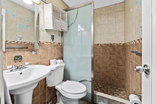 e bagno con servizi igienici, lavandino e doccia. di Lupa Guesthouse affordable family home a Rincon