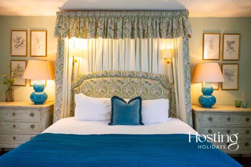 沃金漢的住宿－Luxurious Vineyard Hideaway At Stanlake Park，一间卧室配有一张带两盏灯的蓝色和白色的床。