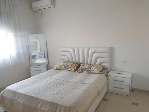 um quarto branco com uma cama e um espelho em Loren em Durrës