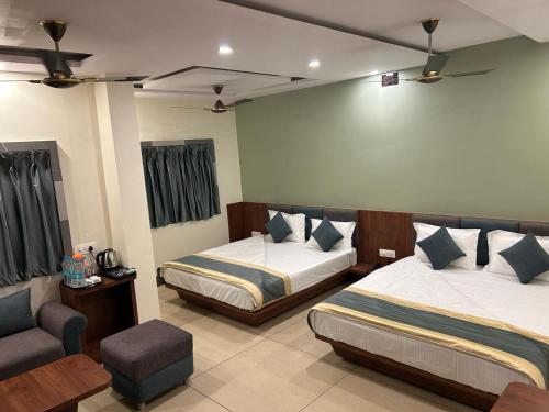 a hotel room with two beds and a chair at Hotel Omkareshwar Inn in Deoghar