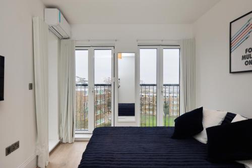 a white bedroom with a bed and a balcony at The Wembley Park Arms - Modern 2BDR Flat with Parking + Balcony in London