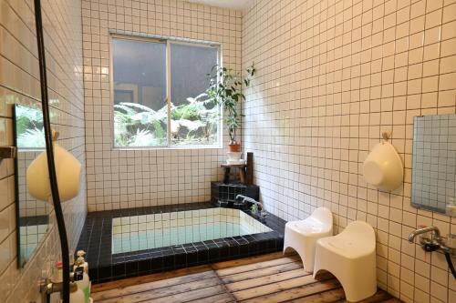 a bathroom with a bath tub with a window at Pension Belnina in Hakuba