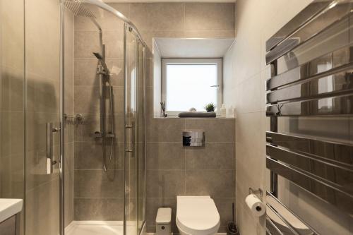 a bathroom with a toilet and a glass shower at The Wembley Park Arms - Modern 2BDR Flat with Parking + Balcony in London