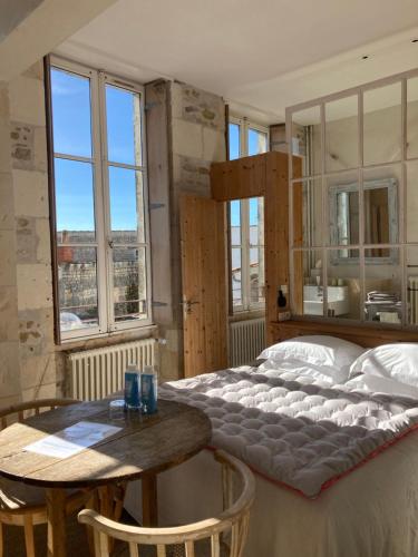ein Schlafzimmer mit einem großen Bett und einem Tisch in der Unterkunft Hôtel Le Sénéchal in Ars-en-Ré
