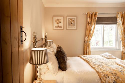 1 dormitorio con 1 cama con lámpara y ventana en Cosy 2 bed cottage in charming village of Christleton - For up to 5 en Christleton