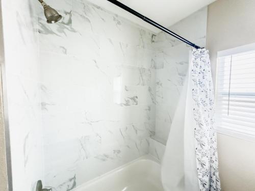 a white bathroom with a tub and a shower curtain at Highland Heights in Tampa