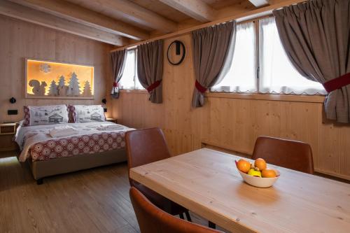 Un dormitorio con una cama y una mesa con un bol de fruta. en Chalet al Tabià en Bormio