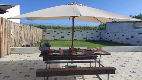 una mesa de picnic con una sombrilla en el patio en WelcomeBuddy - Mosteiros Vineyards (Praia&Sunset), en Mosteiros