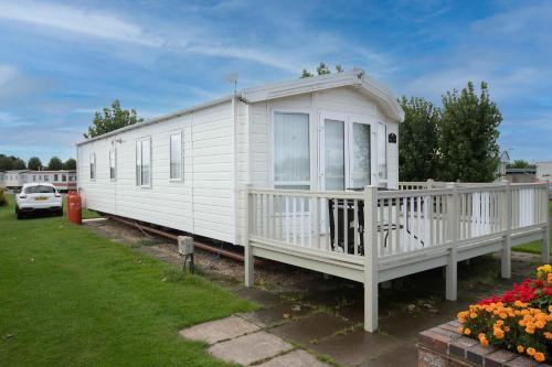 a white mobile home with a porch and flowers at Skegness Holidays in Skegness